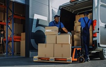 Outside of Logistics Warehouse with Open Door, Delivery Van Loaded with Cardboard Boxes. Truck Delivering Online Orders, Purchases, E-Commerce Goods, Wholesale Merchandise.