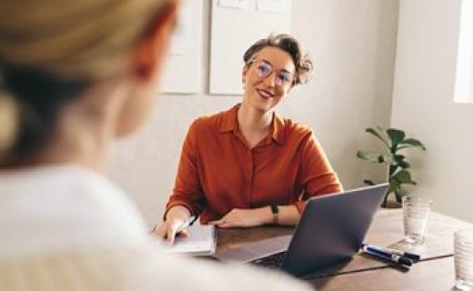 Happy hiring manager smiling while interviewing a job candidate in her office. Cheerful businesswoman having a meeting with a shortlisted job applicant in a creative workplace.