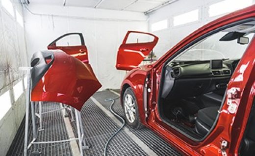 A luxury red car in a paint shop with its doors removed for a fresh coat of paint. High-quality photo