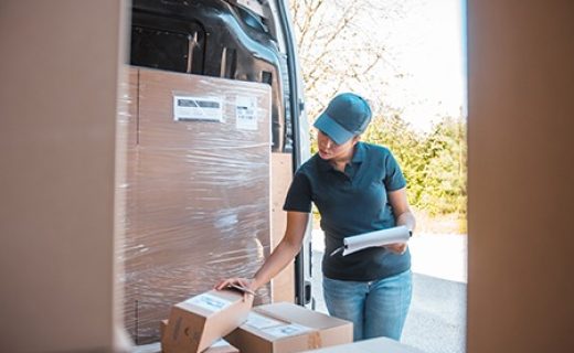 Mixed race female worker checking the labels on the packages inside the delivery van