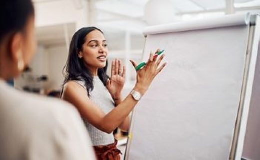 Woman, mentor and whiteboard in office for training, teaching and learning for skill or career development. People, employee and coach or leader at workshop with internship program and motivation