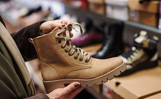 Woman is choosing and buying stylish leather ankle boots in shoe store. Shopping trendy shoes